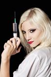 Smiling beautiful young girl in the image of nurse with syringe 