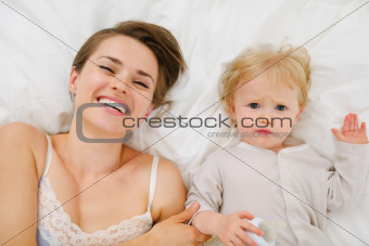 Portrait of mother and baby laying in bed. Upper view