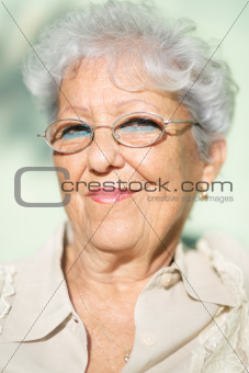 Old woman with eyeglasses smiling and looking at camera