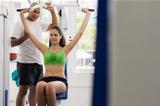 Personal trainer helping woman training in wellness club