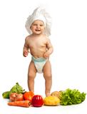 Little boy in chef's hat among fresh vegetables