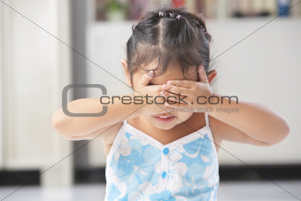 Little girl playing peekaboo or crying