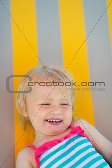 Portrait of laughing baby laying on sunbed