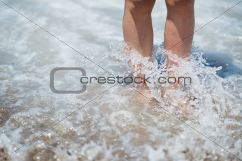 Closeup on legs in sea wave splashes