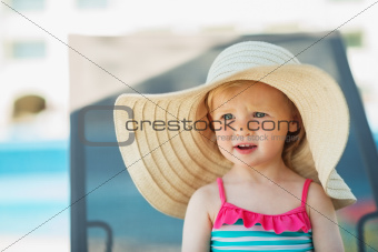 Portrait of baby in hat sitting on sunbed