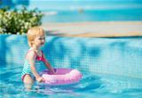 Baby standing in pool with inflatable ring
