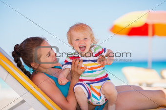 Portrait of excited baby with mother on beach
