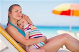 Relaxed mother on sun bed embracing baby