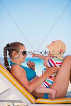 Mother with baby on beach playing with sunglasses