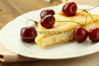 Sweet crepe pancake with  cherries on a wooden table