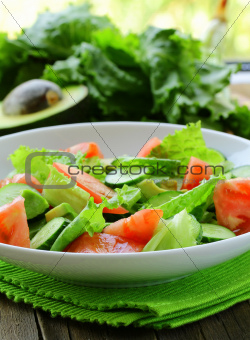 fresh salad with avocado and tomato on a wooden table