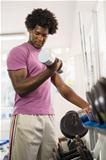 Young black man taking weights from rack in gym