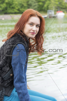 Young woman sitting by a lake