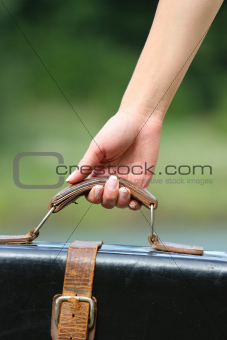 woman's hand holding a suitcase outside