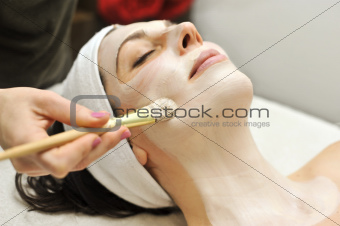 a beautician applies a clay mask as part of a beauty treatment