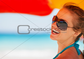 Portrait of smiling woman on beach under umbrella