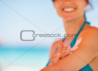 Closeup on female hand applying sun block creme on arm