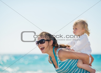 Kid piggybacking mother on beach