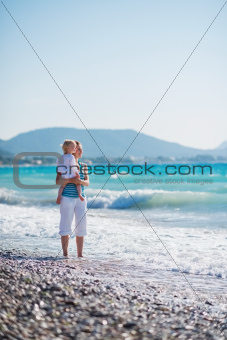 Mother with baby on sea coast looking into distance