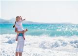 Mother on sea shore with baby pointing on copy space