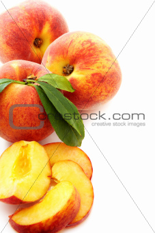 Ripe peach with green leaves.