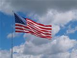 American Flag Flying in front of a Blue Cloudy sky