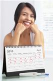 Happy woman with positive pregnancy test and calendar