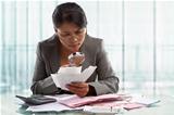 Asian businesswoman checking bills using magnifying glass