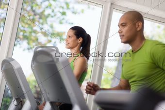 Young people exercising and running on treadmill in gym