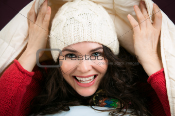 Happy woman peeking out from under blankets