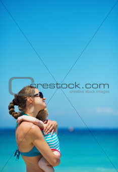 Mother hugging baby on beach