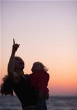 Silhouette of mother with baby in dusk pointing up on copy space