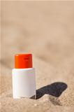 Bottle of sun block creme on sand