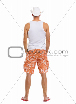 Full length portrait of on vacation man in shorts. Rear view