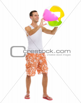 Resting on vacation happy young man playing with beach ball