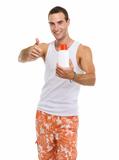 Happy young guy showing sun screen creme and thumbs up