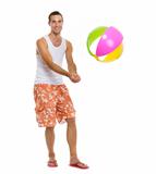 On vacation happy young man playing volleyball with beach ball