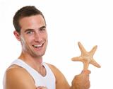 Portrait of on vacation smiling young man with sea star