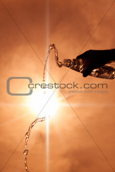 hand holding a bottle of water with sunlight background