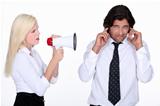 woman talking through a megaphone and a man plugging his ears