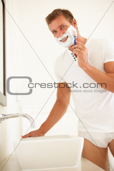 Young Man Shaving In Bathroom Mirror