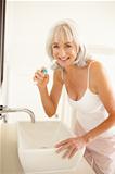 Senior Woman Brushing Teeth In Bathroom