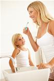 Mother And Daughter Brushing Teeth In Bathroom Together