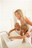 Mother And Children Brushing Teeth In Bathroom Together