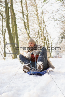 Man Sledging Through Snowy Woodland