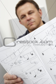 Man Reading Assembly Instructions For Flat Pack Furniture