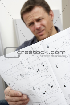 Puzzled Man Reading Assembly Instructions For Flat Pack Furniture
