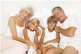 Grandparents Relaxing On Bed With Grandchildren