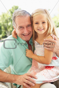 Portrait Of Grandfather With Granddaughter Relaxing Together On Sofa