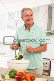 Senior Man Preparing Salad In Modern Kitchen